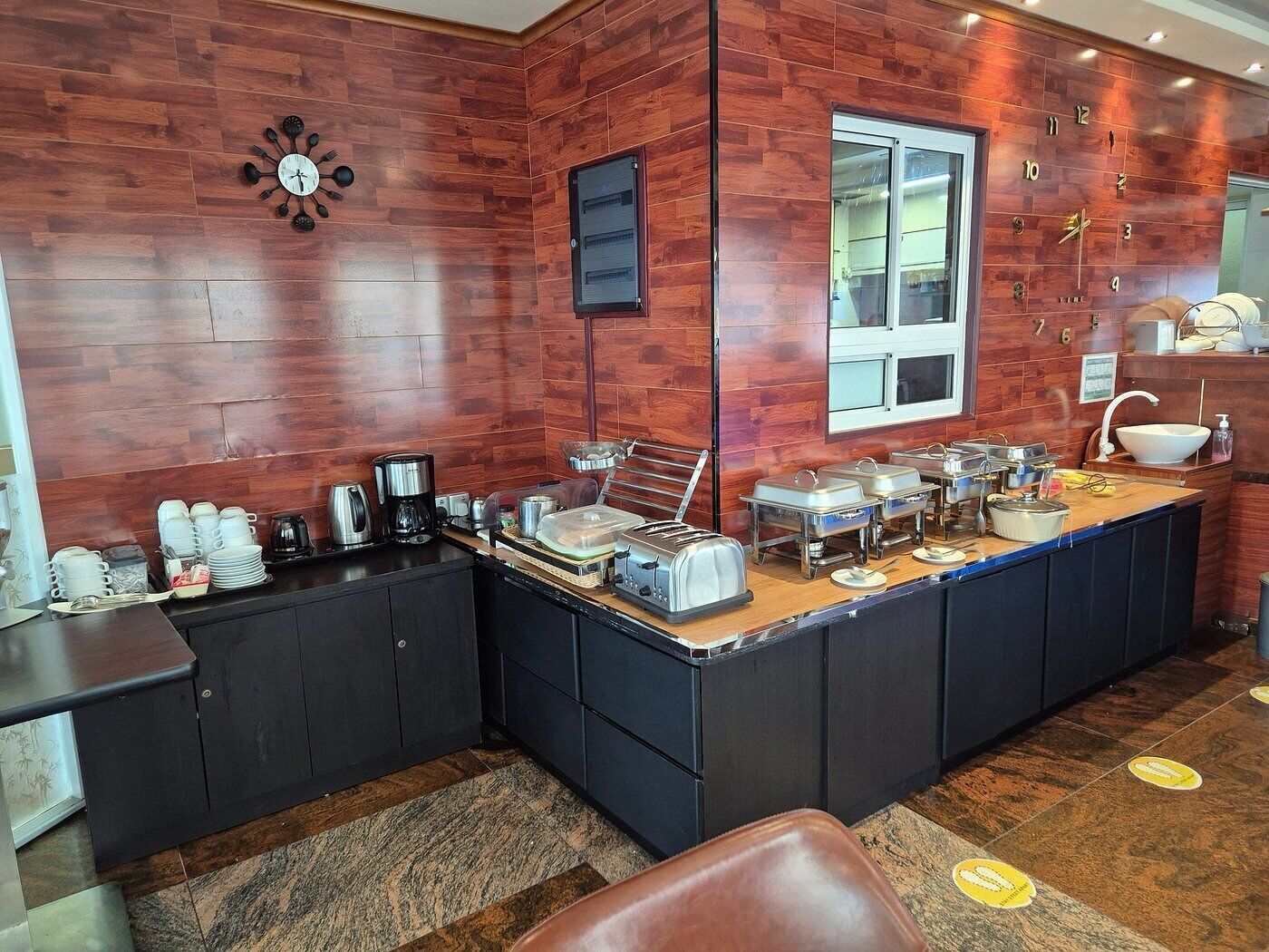 A modern kitchen with wooden walls, a large window, and a variety of appliances and utensils.