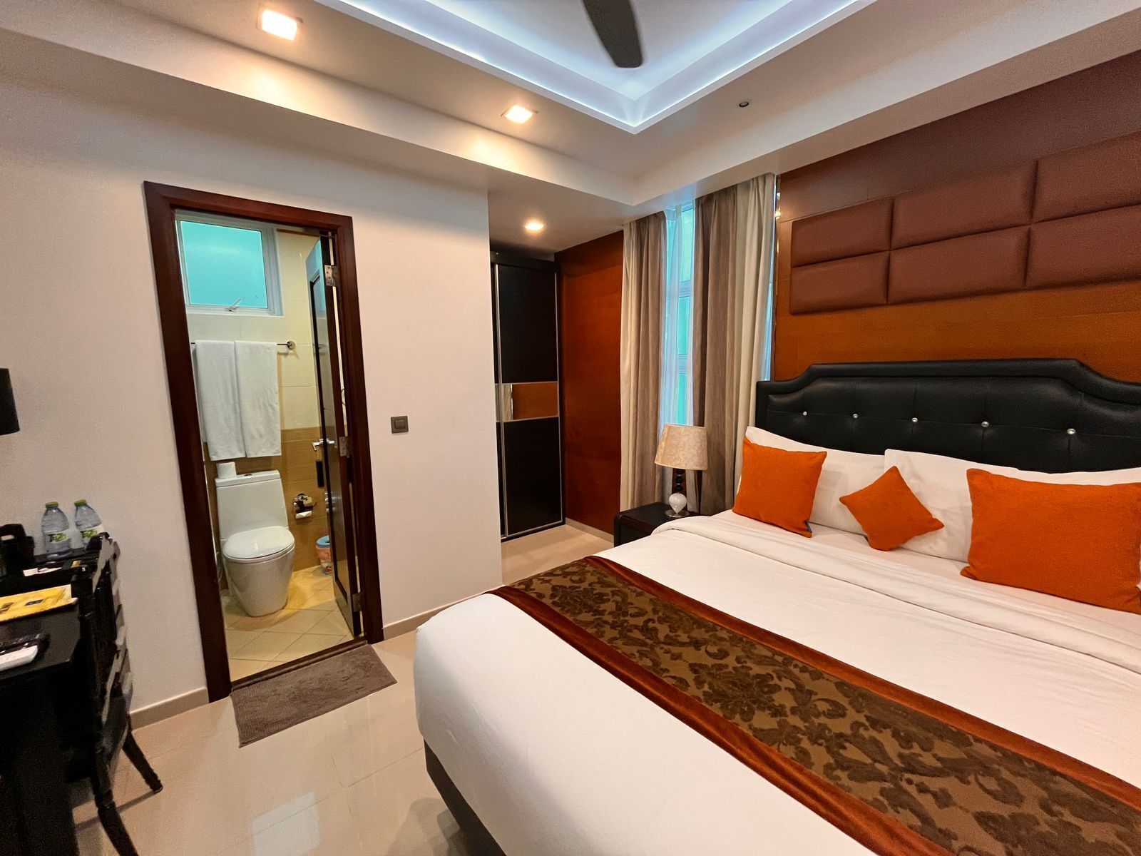 A hotel room with a large bed, a desk with a chair, a bathroom, and a view of the outside.
