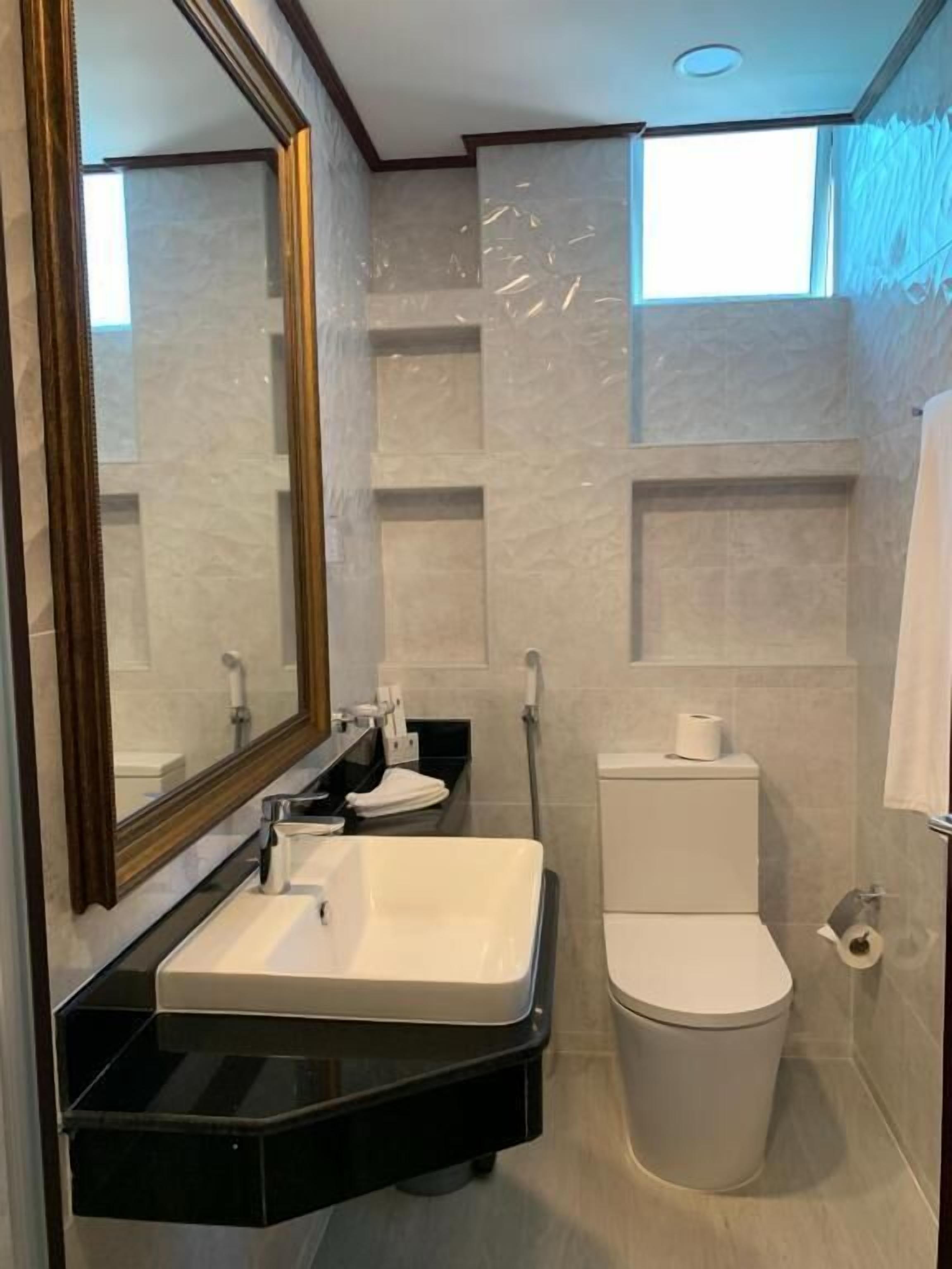 Une salle de bain moderne avec un grand miroir, un lavabo, des toilettes et un espace douche.