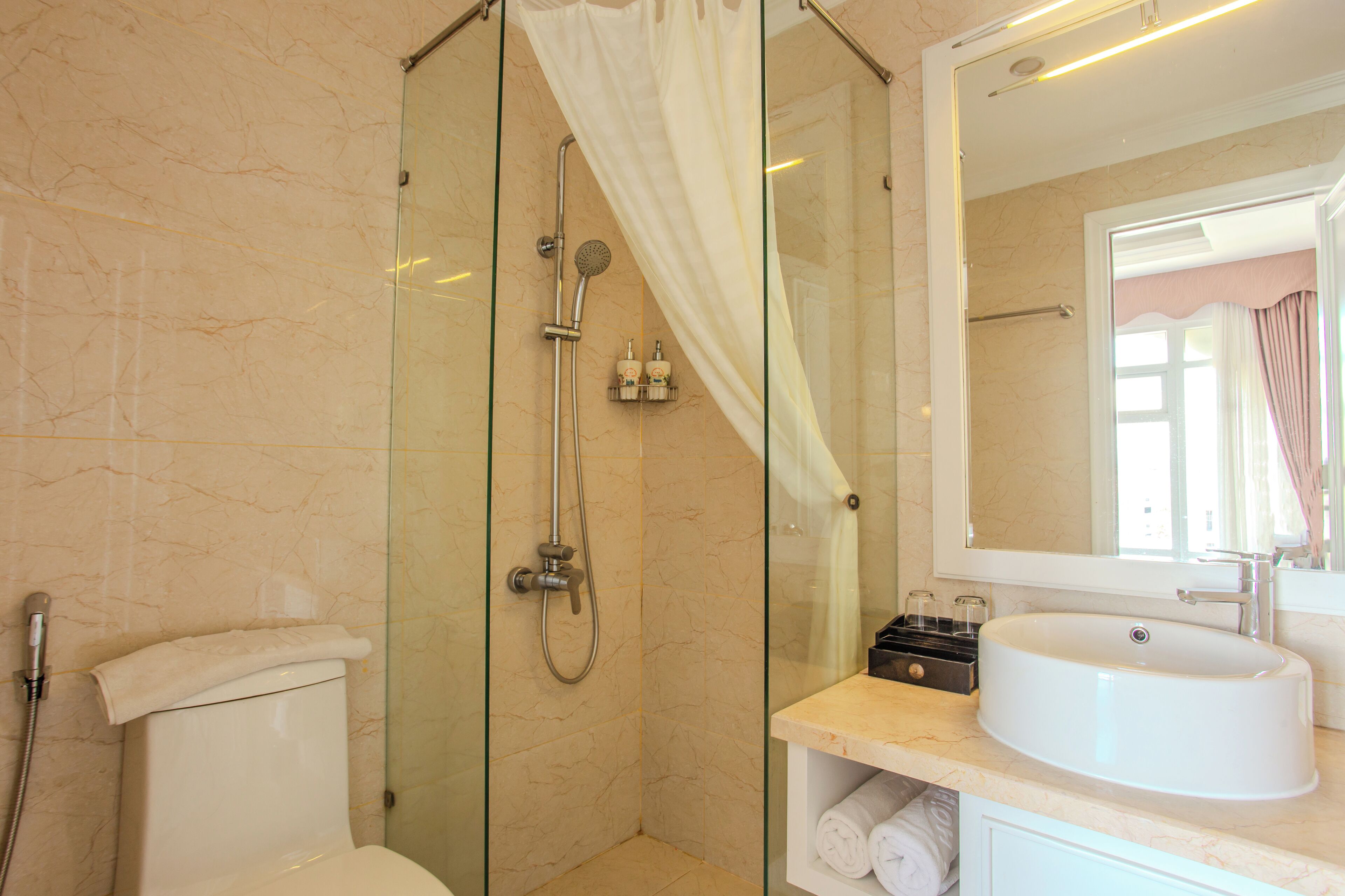 A modern bathroom with a glass-enclosed shower, a toilet, and a sink with a mirror above it.