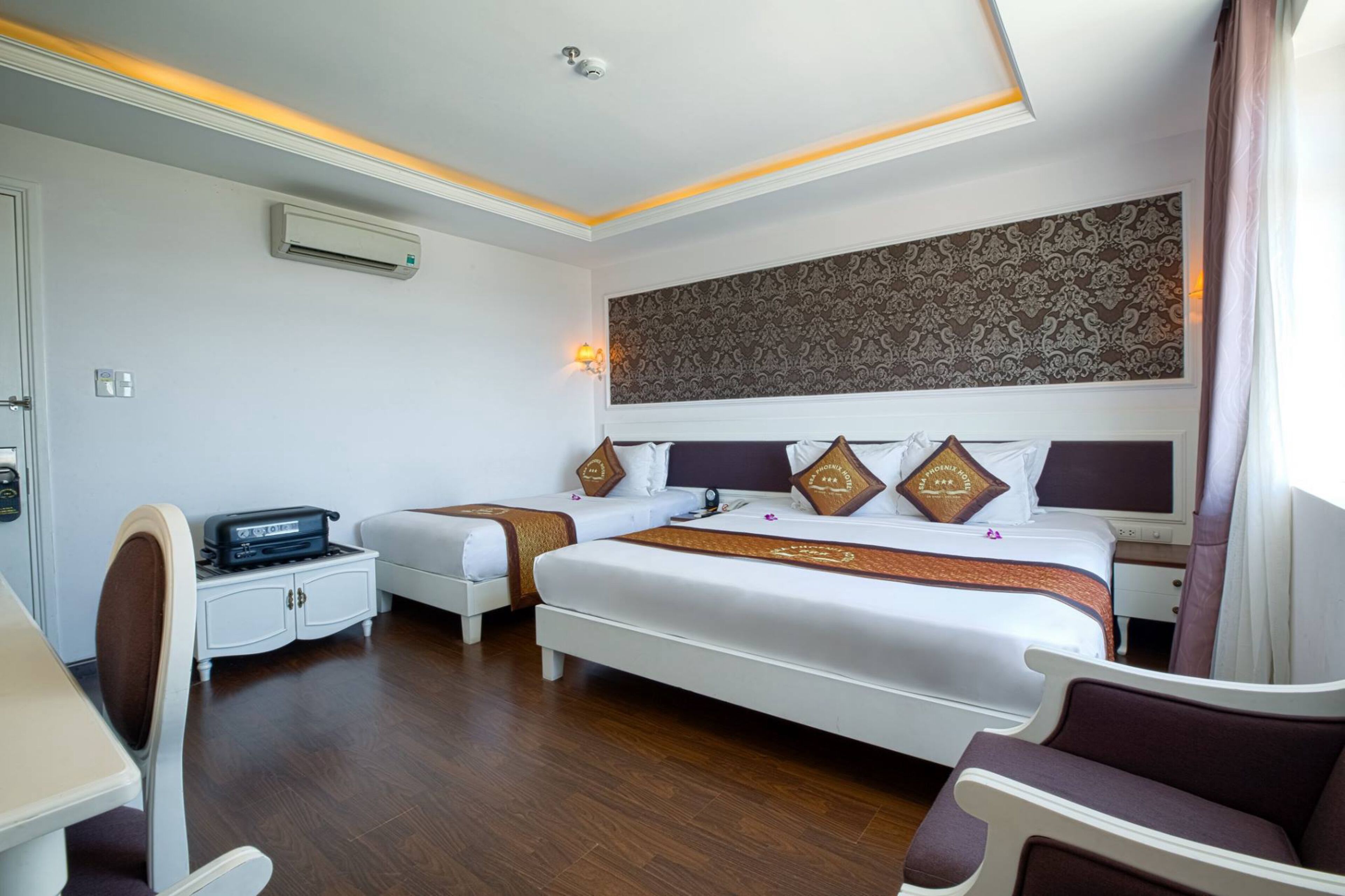 A hotel room with two beds, a desk, a chair, and a large decorative wall.