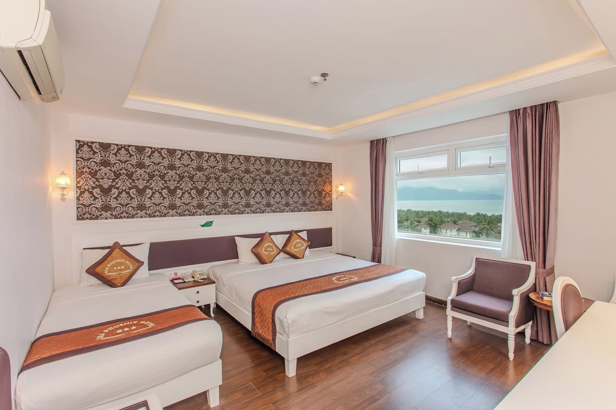 Une chambre d’hôtel avec deux lits, une chaise, une petite table et une vue sur la mer.