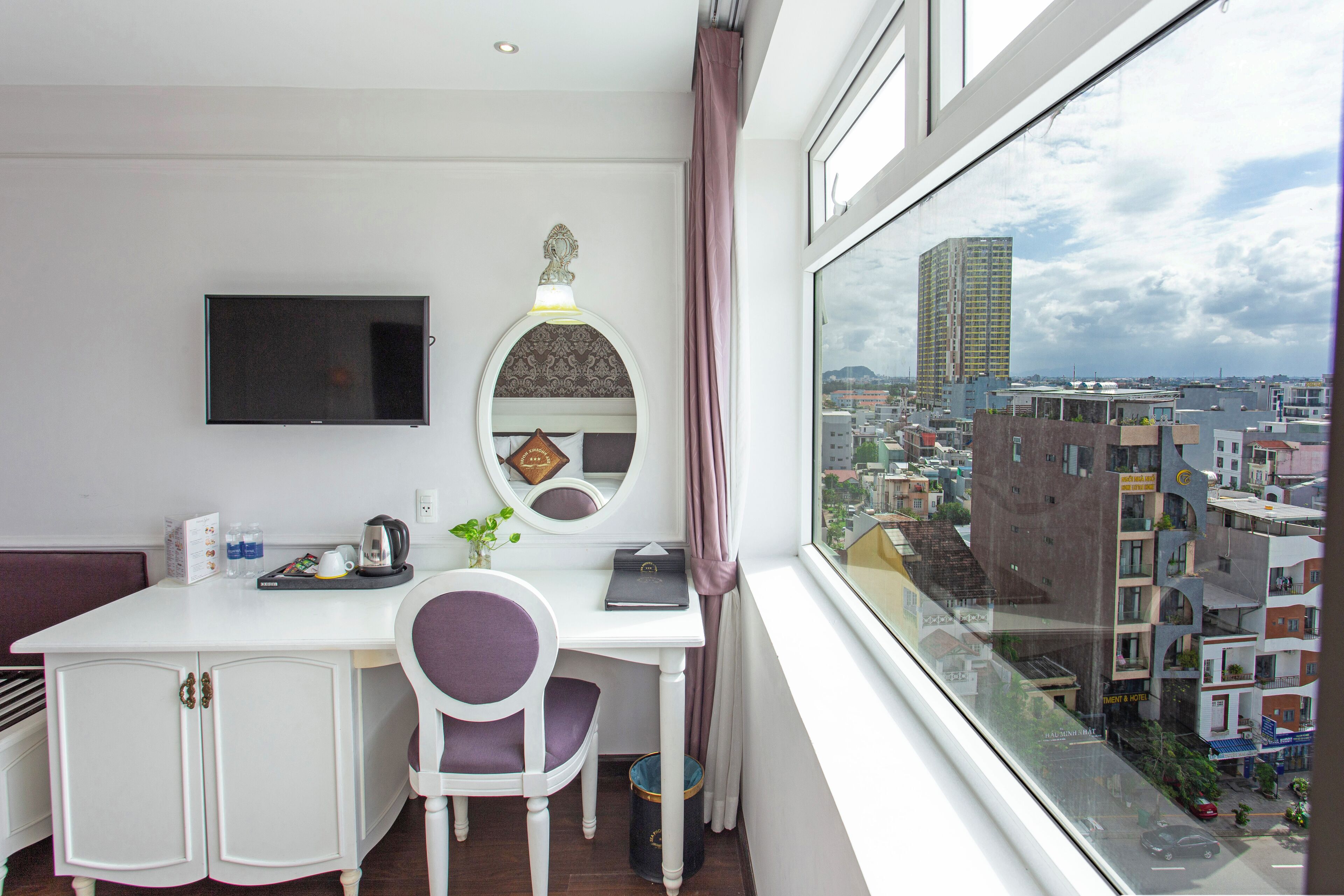 Habitación de hotel con escritorio, silla y un ventanal que ofrece vistas a la ciudad.