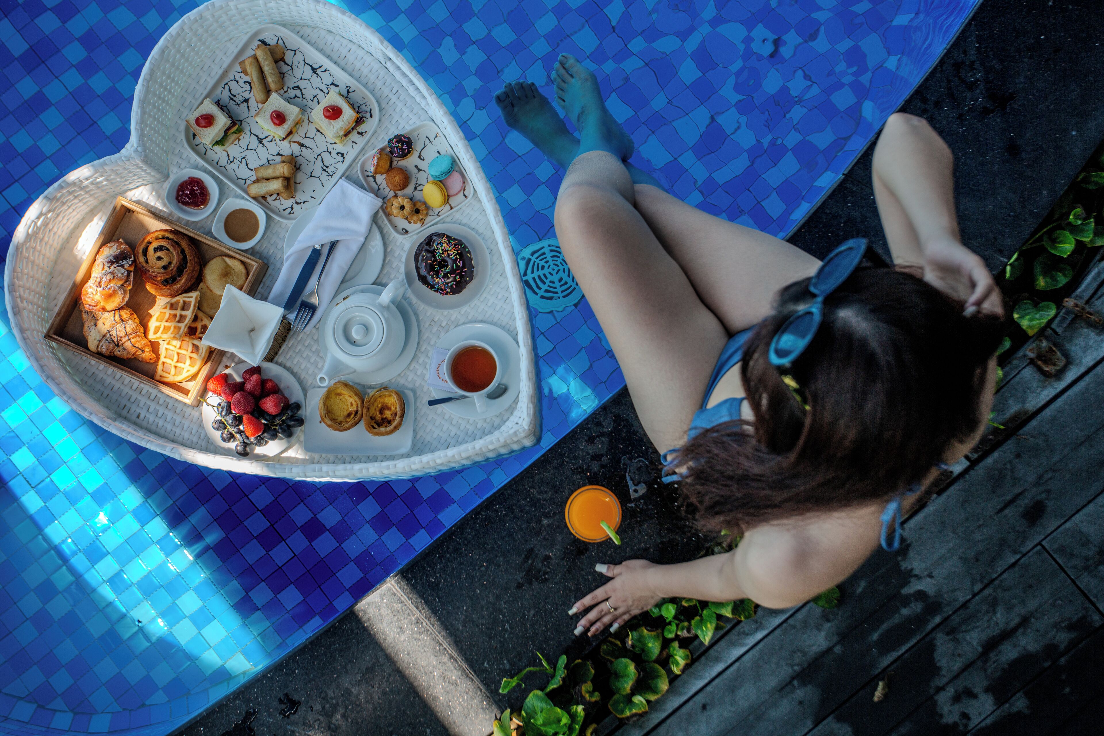 A poolside setting with a tray of food and a person relaxing by the pool.