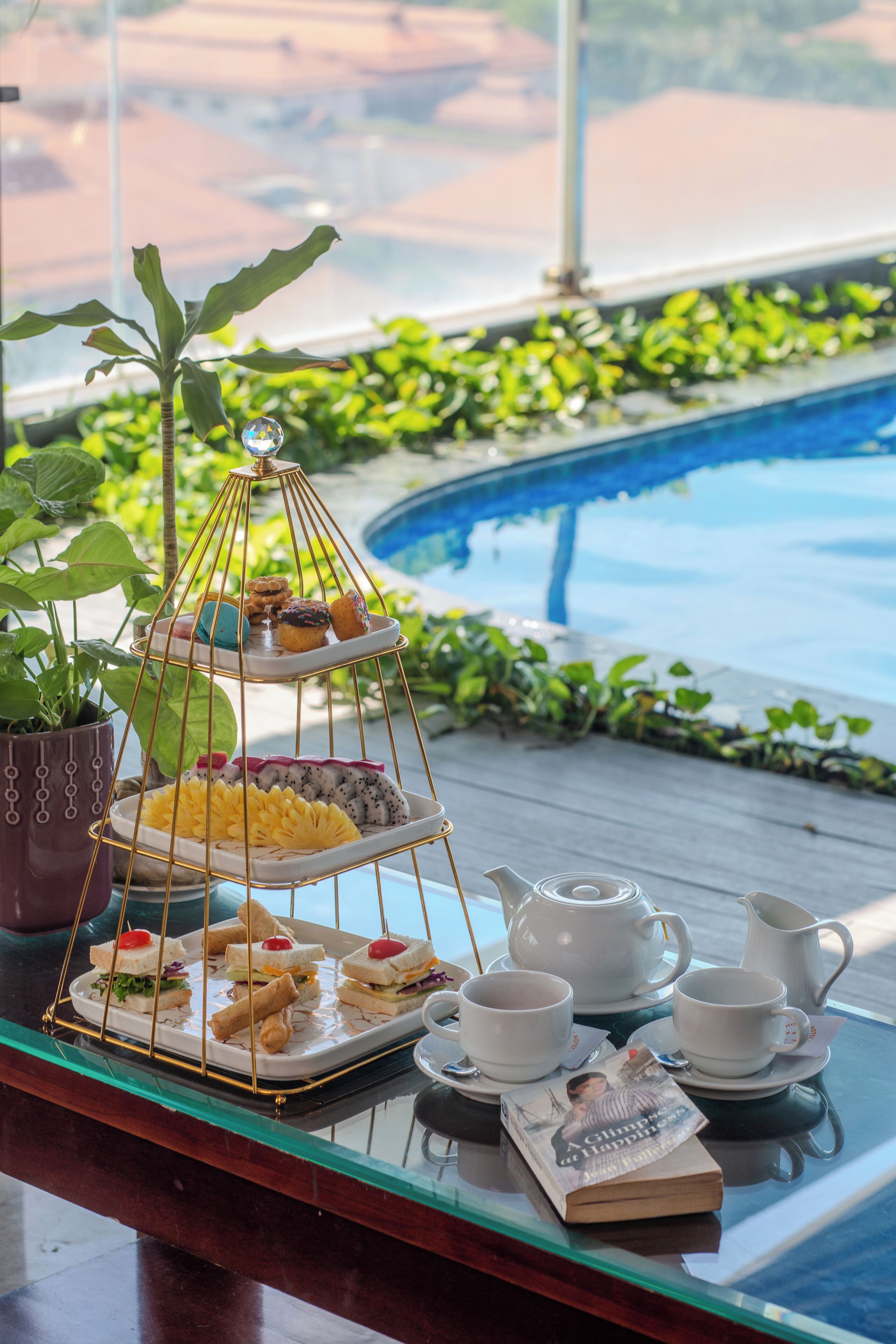 A tray with food and drinks by a poolside with a view.