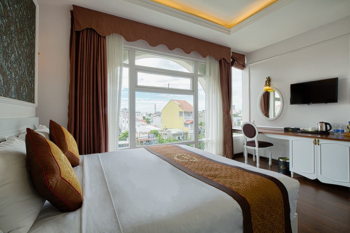 Une chambre d’hôtel avec un grand lit, un bureau avec une chaise, une télévision et une vue sur la ville.