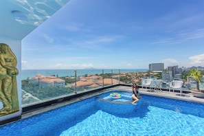 Ein Infinity-Pool auf dem Dach mit freiem Blick auf Stadt und Meer.