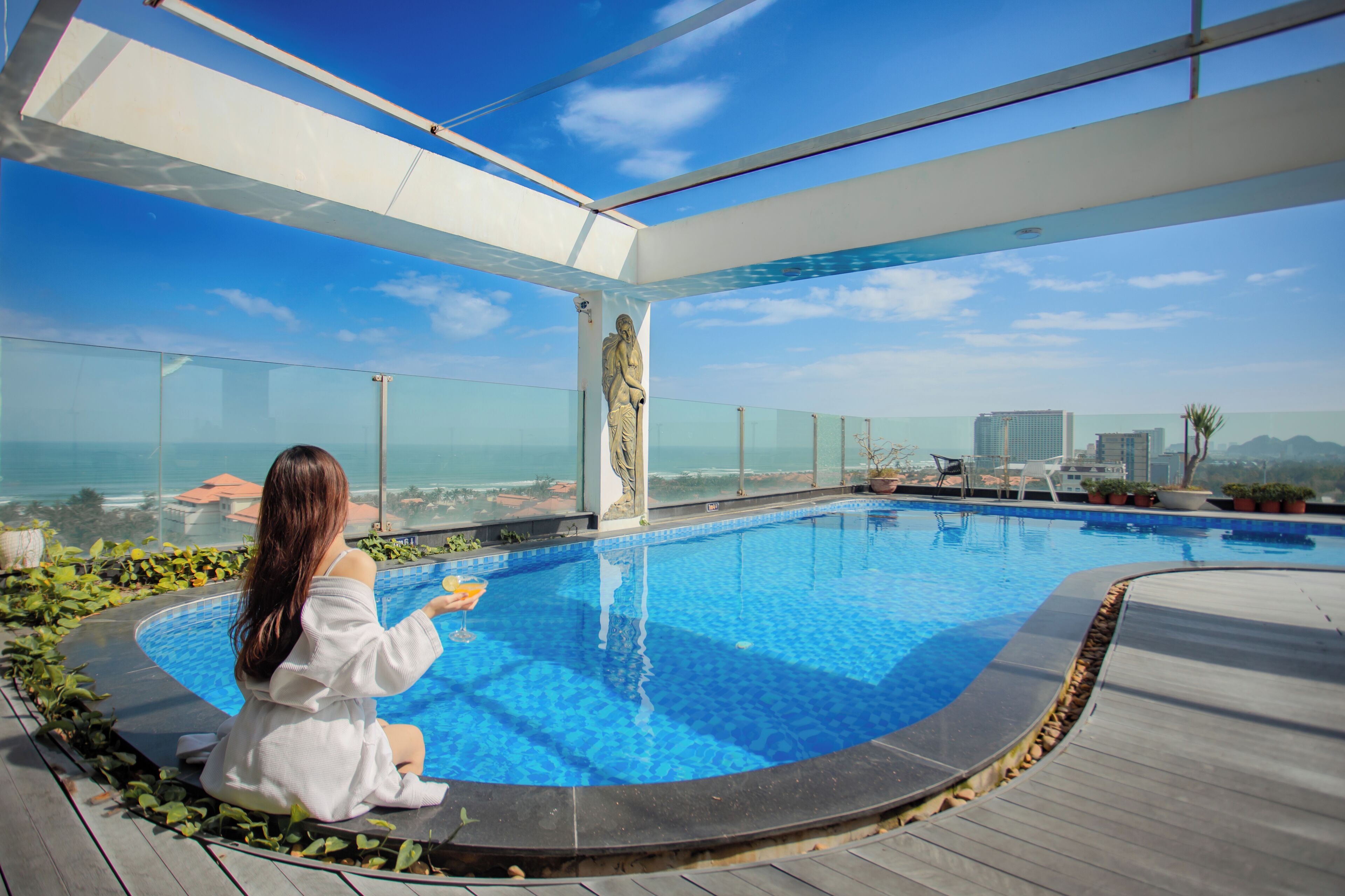 A woman sitting by a pool with a city view.