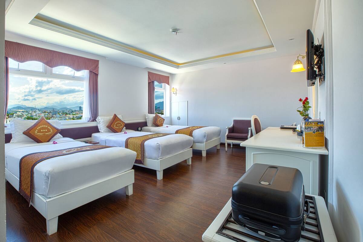 Une chambre d’hôtel avec deux lits, un bureau et une valise.