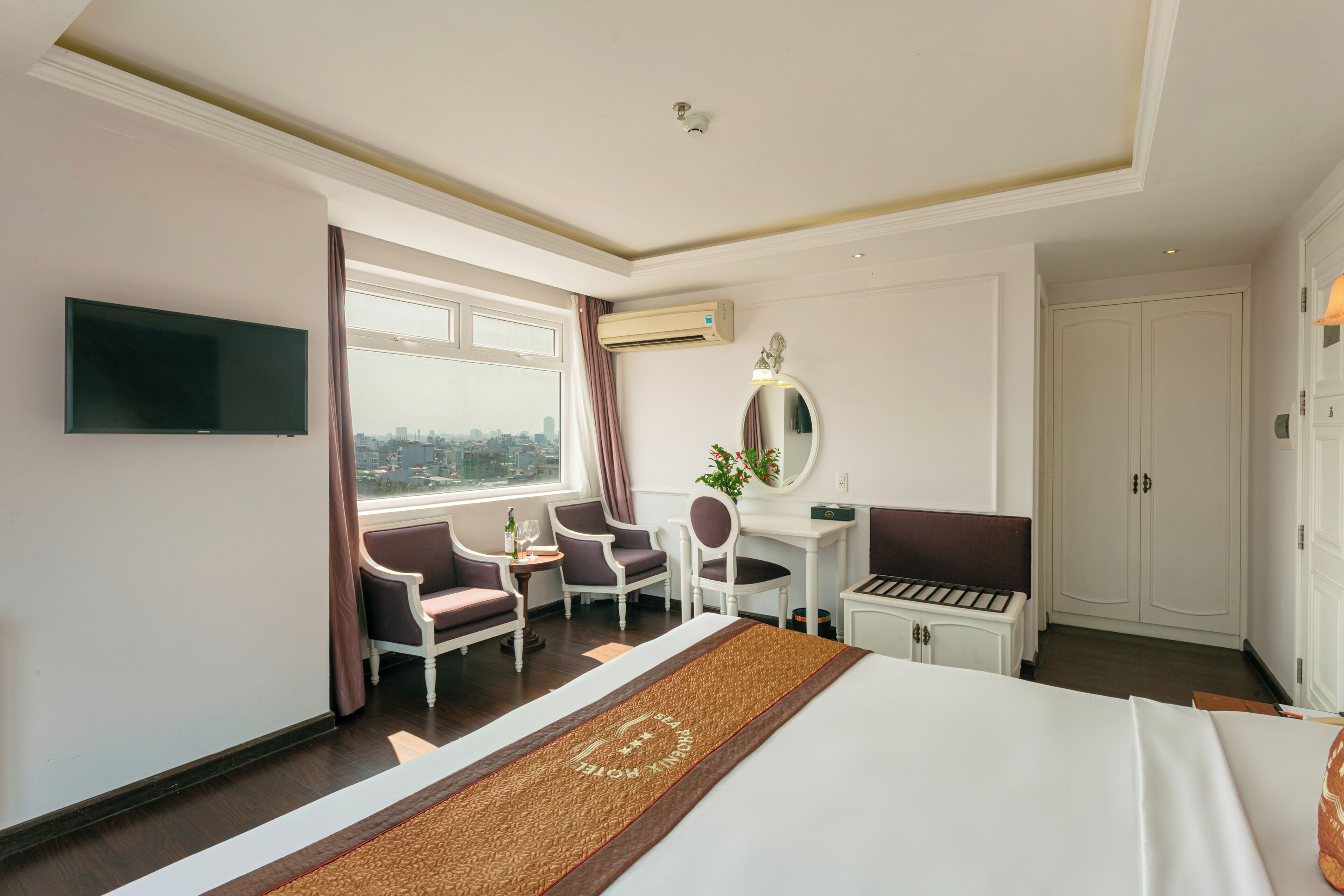 Une chambre d’hôtel équipée d’un lit, d’un bureau, d’une chaise, d’une télévision et d’une fenêtre avec des rideaux.
