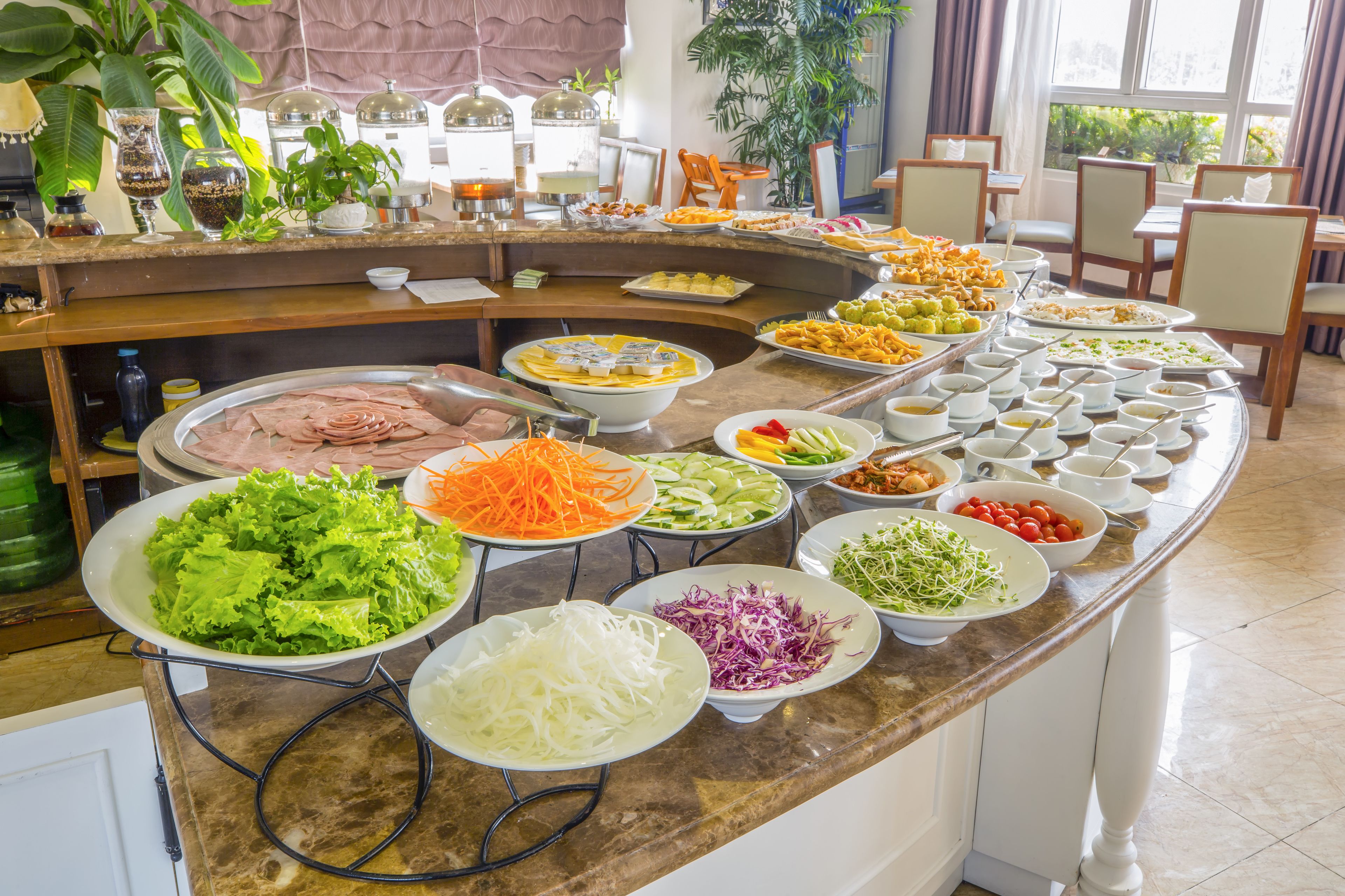 Ein Buffet mit verschiedenen Speisen, darunter Salate, Fleisch und Gemüse.