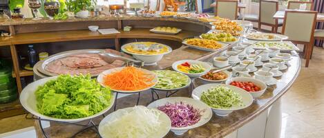 A buffet with various food items including salads, meats, and vegetables.
