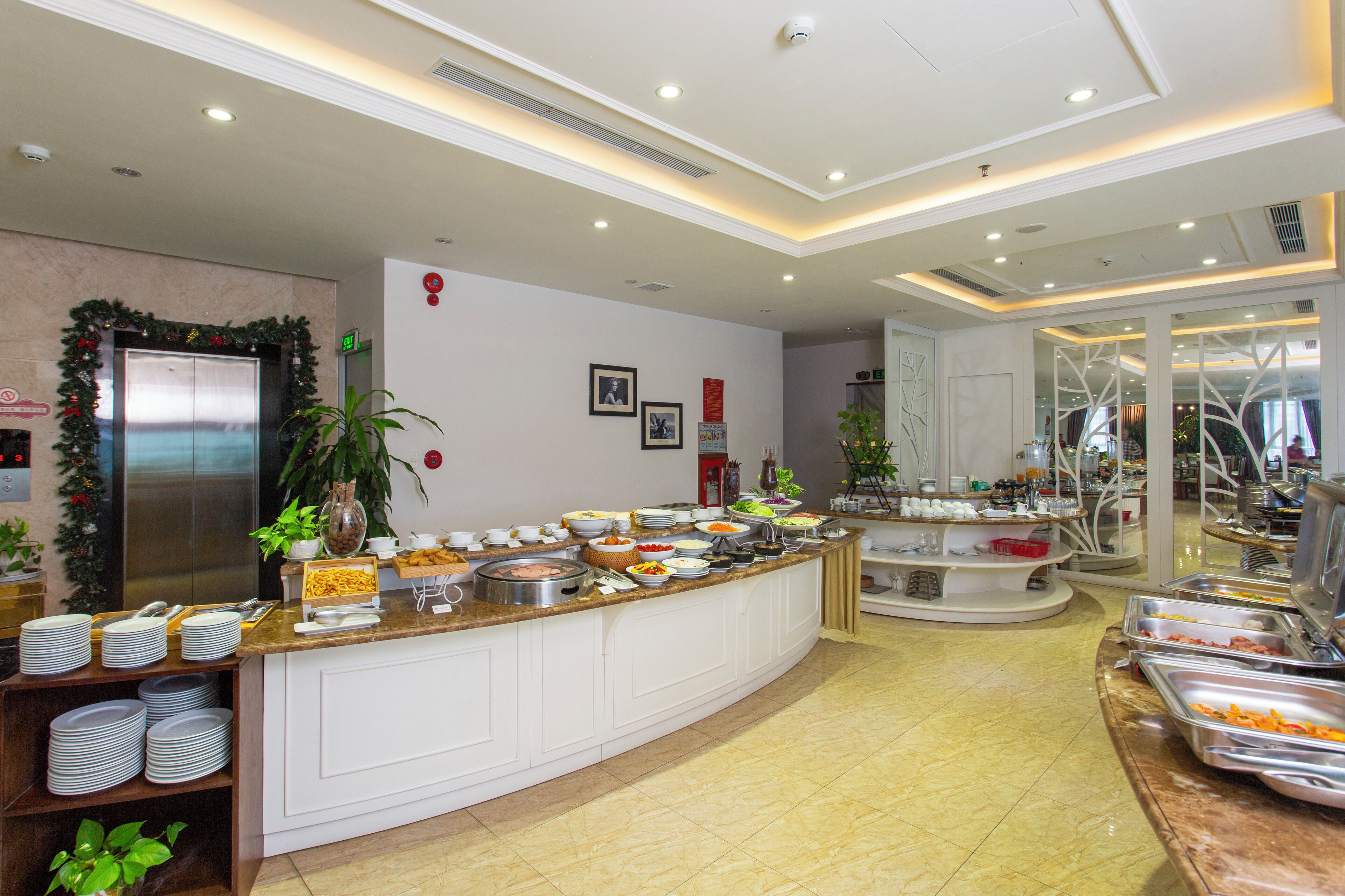 Buffet-alue, jossa on useita ruokapisteitä, jääkaappi ja kasvi.