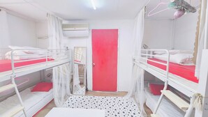 Una habitación con literas, una puerta roja y un ventilador de techo blanco.