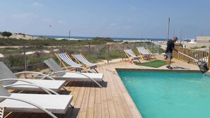 Una piscina al aire libre de temporada, sombrillas