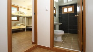 Une petite pièce comprenant un lit superposé, des toilettes et un petit lavabo.