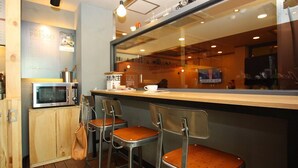 Un café avec un comptoir en bois, des chaises en métal, un four à micro-ondes et une tasse de café posée sur le comptoir.