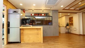Une cuisine moderne avec un comptoir en bois, un réfrigérateur et une fenêtre donnant sur une boutique de yaourts.