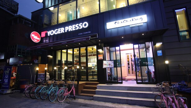 Un bâtiment avec une enseigne indiquant « YOGERPRESSO » et « MAISON D’HÔTES ».