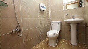 Une salle de bain équipée de toilettes, d’un lavabo et d’une douche.