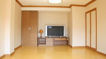 Una habitación con un armario de madera, un televisor sobre un mueble de madera y una lámpara.