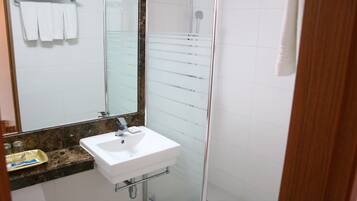 A bathroom with a white sink, a mirror, and a glass shower enclosure.