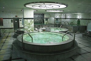Un área de spa con dos jacuzzis circulares, una pared de mármol e iluminación circular en el techo.