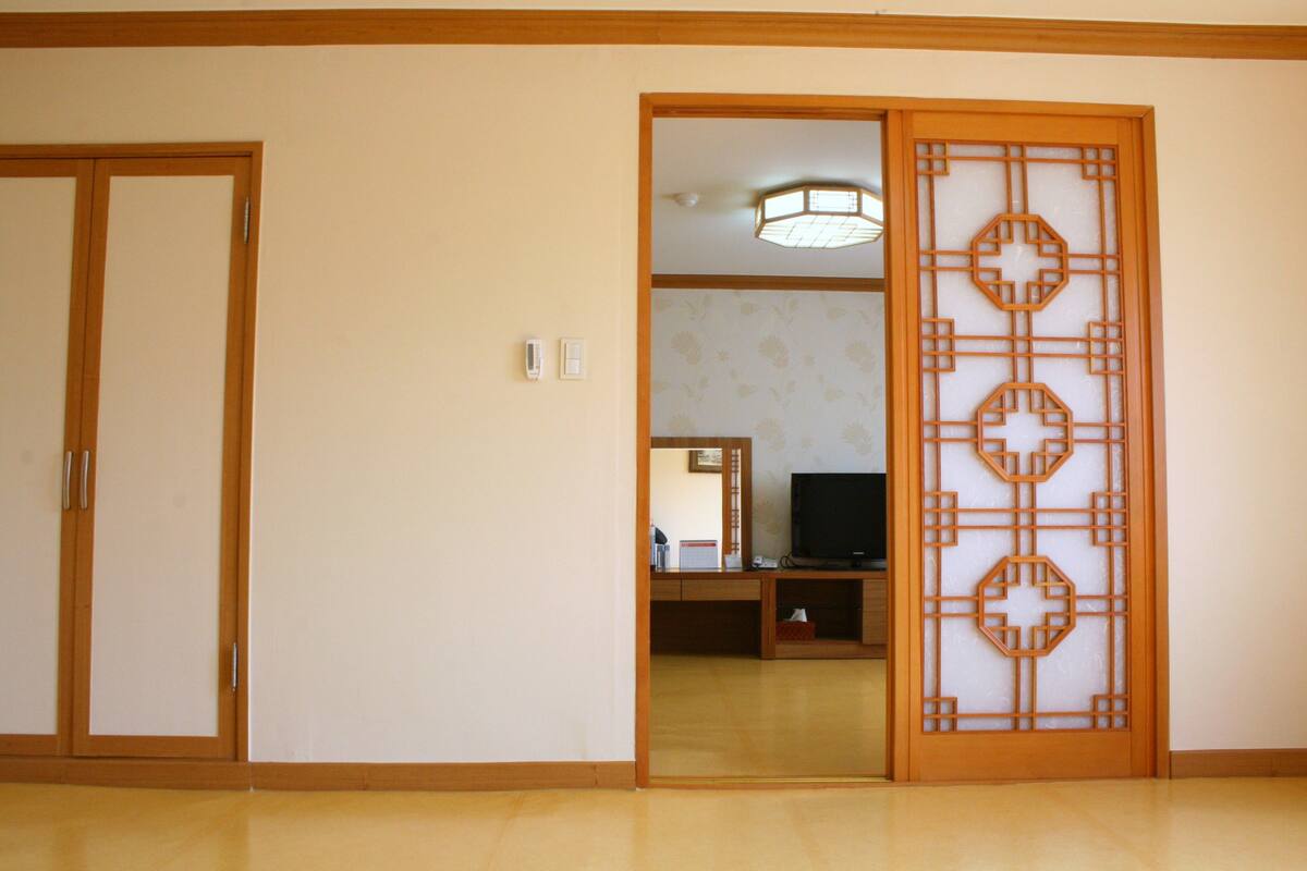 A room with a wooden door, a television, and a desk with a mirror.