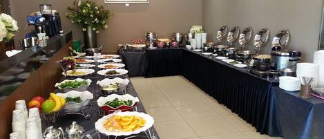 A buffet setup with various food items and serving utensils.
