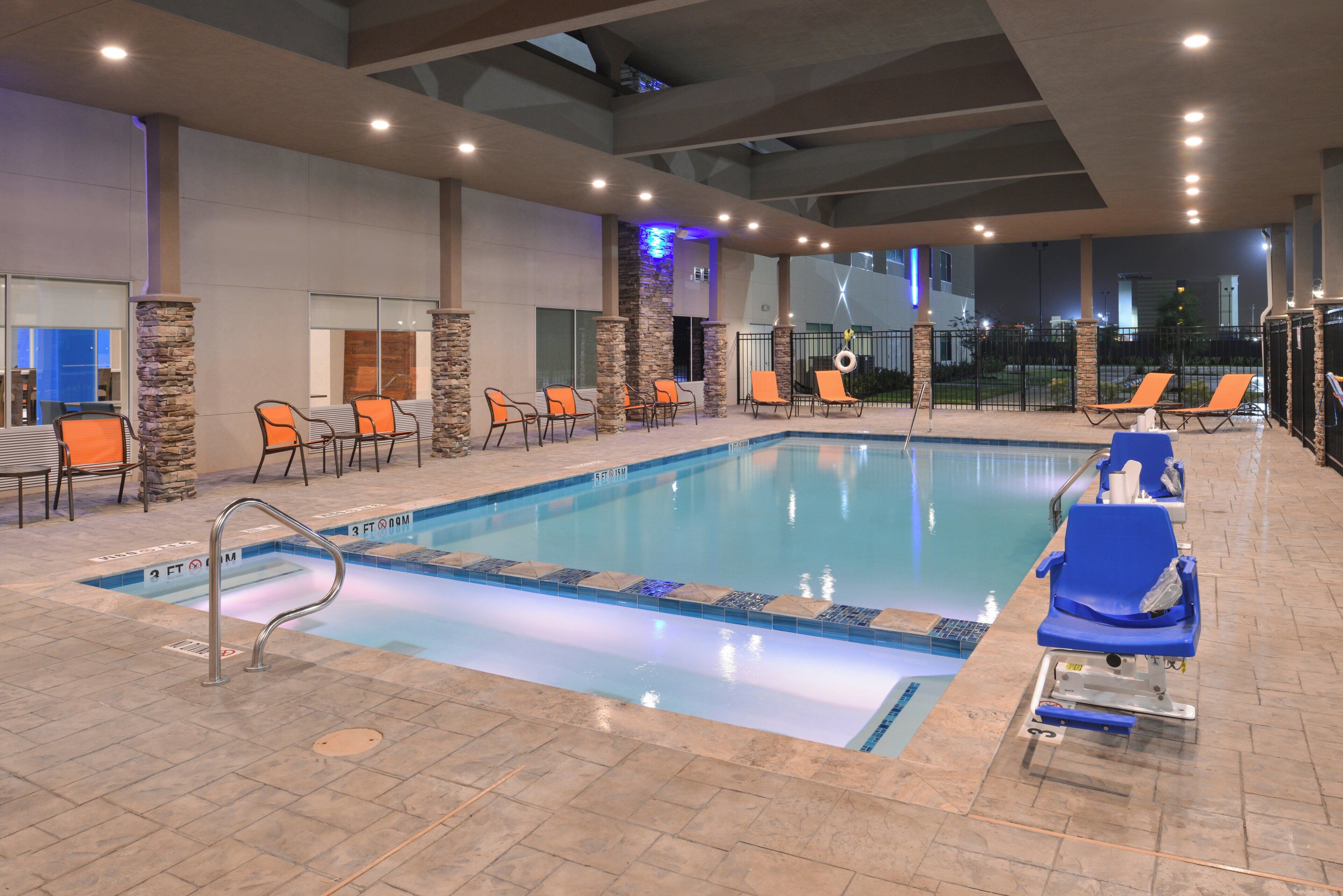 Una piscina interior con sillones de descanso y un pilar de piedra.