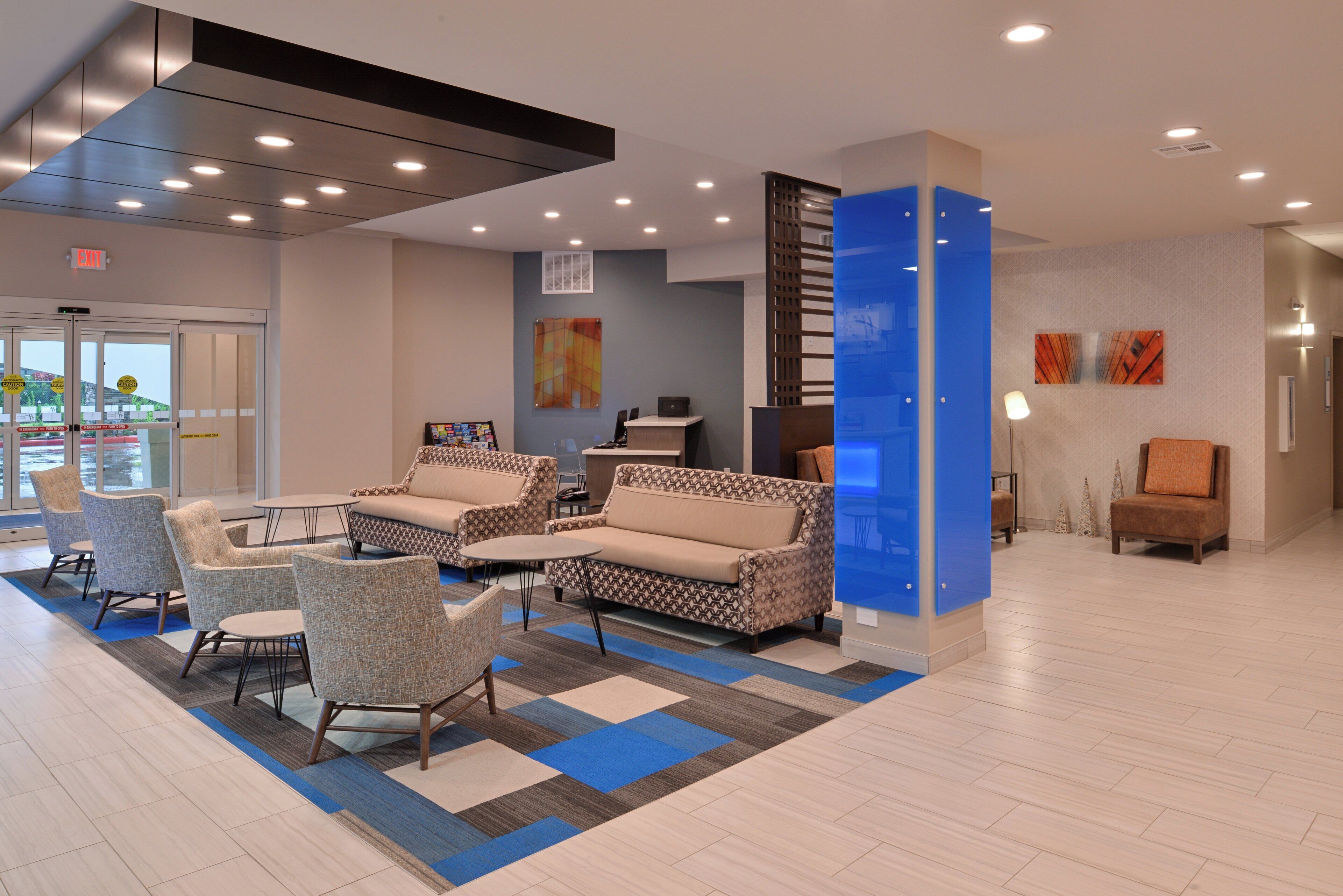 Un hall con asientos, una recepción y una pared azul destacada.
