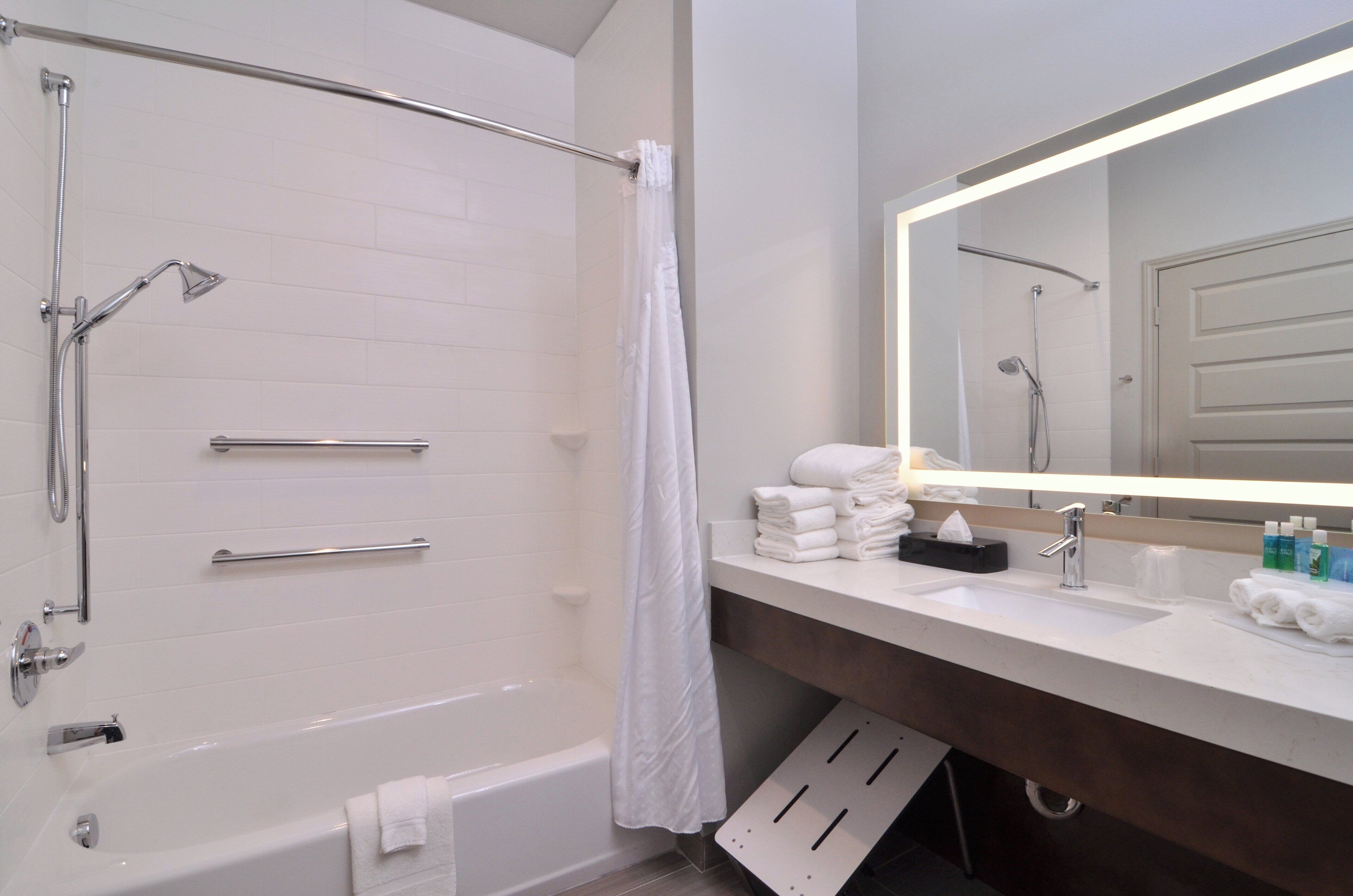 A modern bathroom with a bathtub, shower, and a vanity with a mirror.
