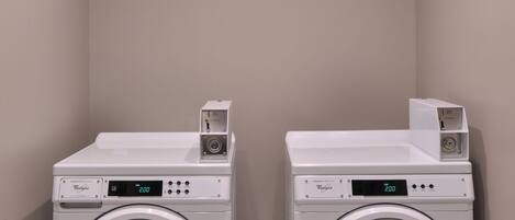 Two front-loading Whirlpool washers in a laundry room with a tiled floor and plain walls.