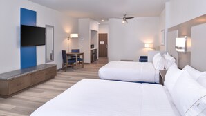 A hotel room with two beds, a desk, a chair, a TV mounted on the wall, and a ceiling fan.