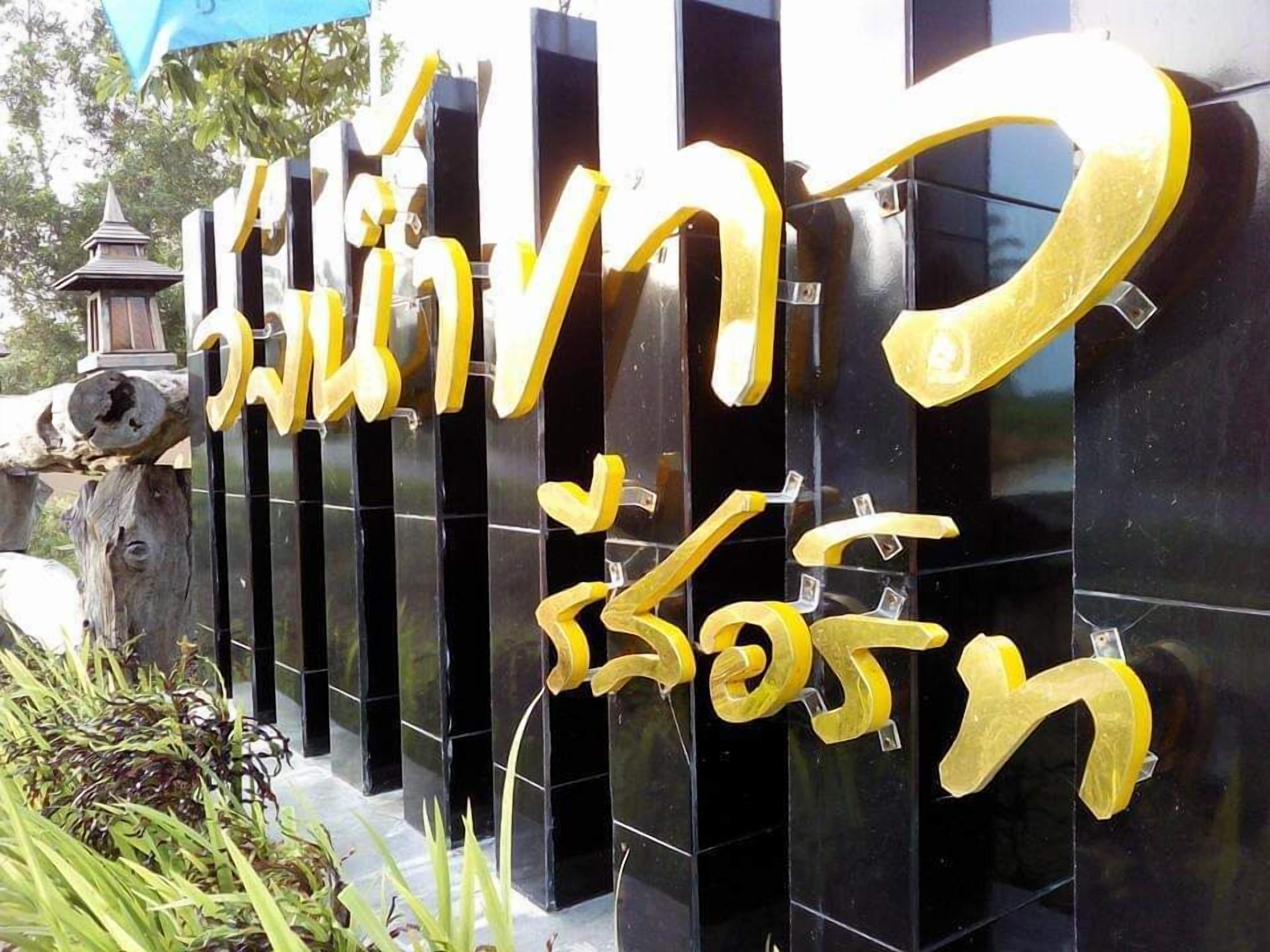 A black wall with golden letters spelling out a name in two languages.