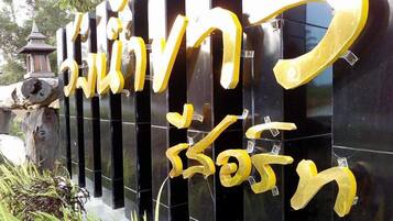 A black wall with golden letters spelling out a name in two languages.