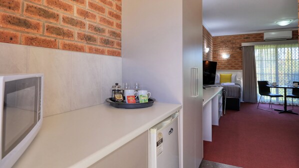 Una kitchenette con cafetera, tazas y una bandeja de cápsulas de café.