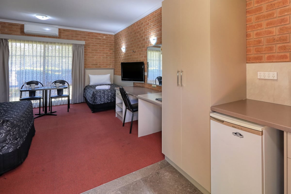 Une chambre d’hôtel équipée d’un lit, d’un bureau, d’une chaise, d’une télévision, d’un four à micro-ondes et d’un petit réfrigérateur.