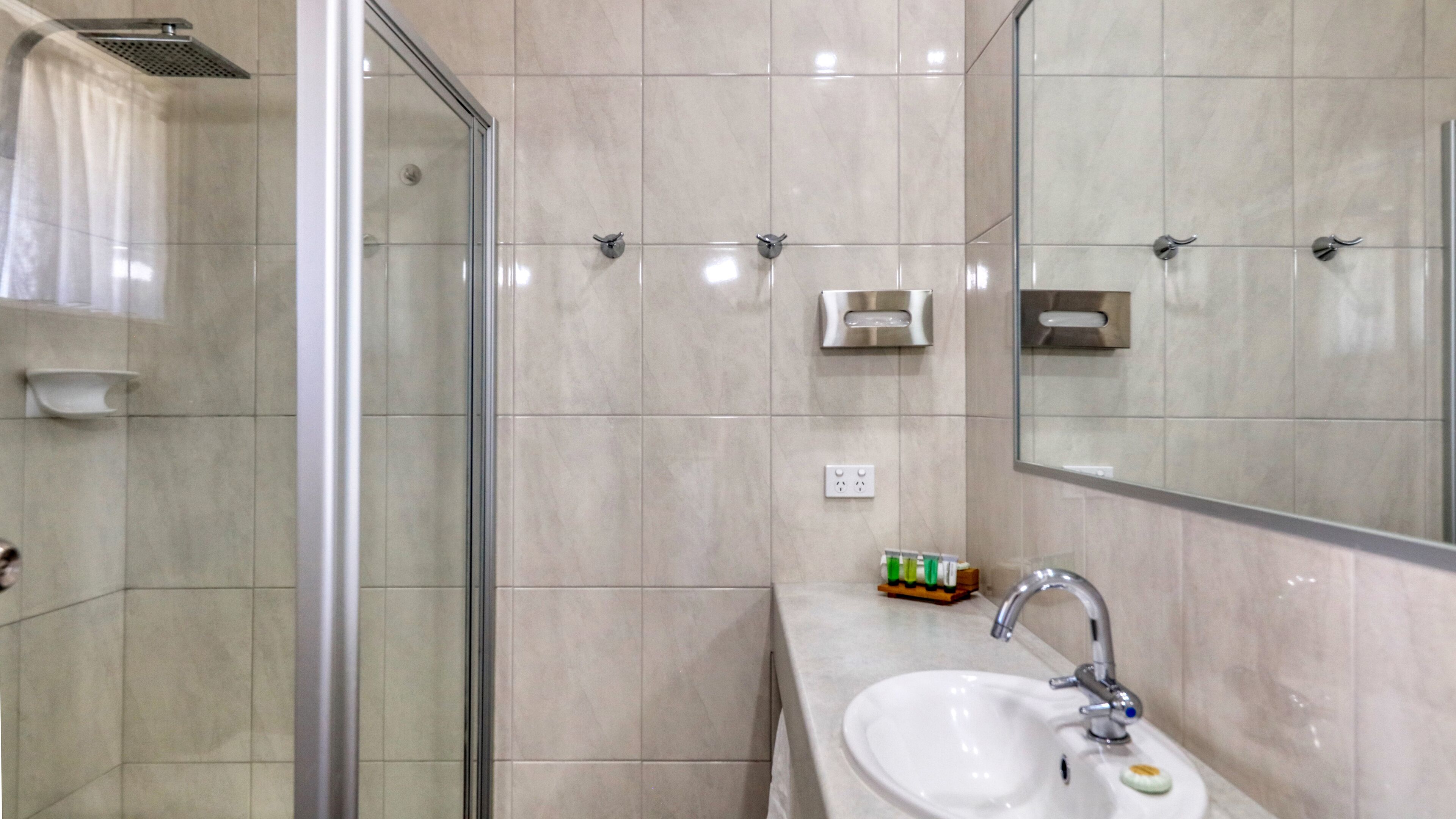 A modern bathroom with a glass shower enclosure, a sink with a mirror, and a towel rack.
