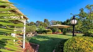 Un jardin bien entretenu, agrémenté d’une pergola, d’un banc en pierre et d’une pelouse.