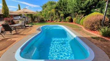 Una piscina al aire libre, sillones reclinables de piscina