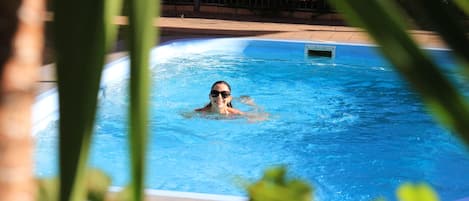 Una piscina al aire libre, sillones reclinables de piscina