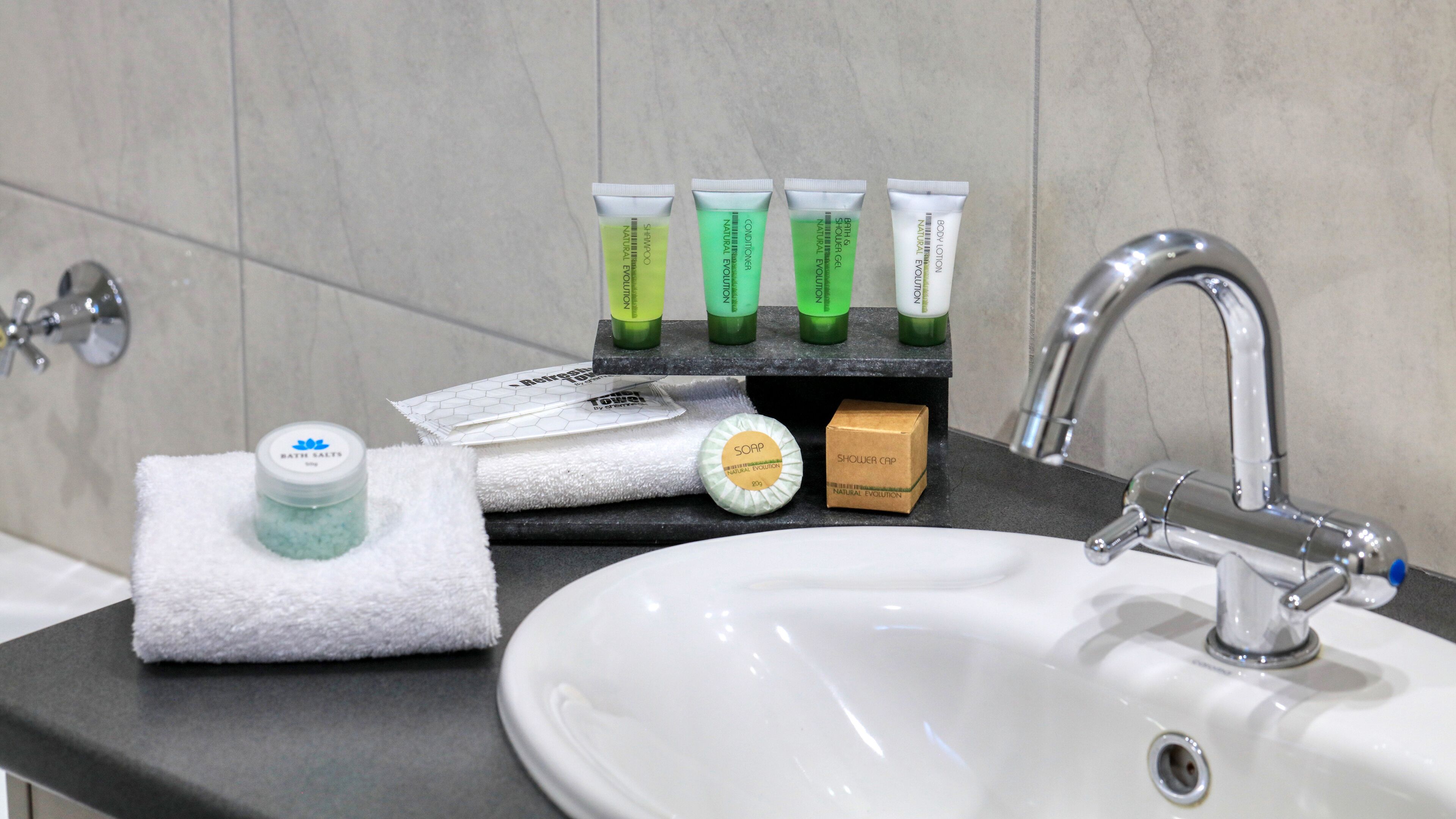 A bathroom sink with toiletries including a bar of soap, a towel, and several tubes of lotion.