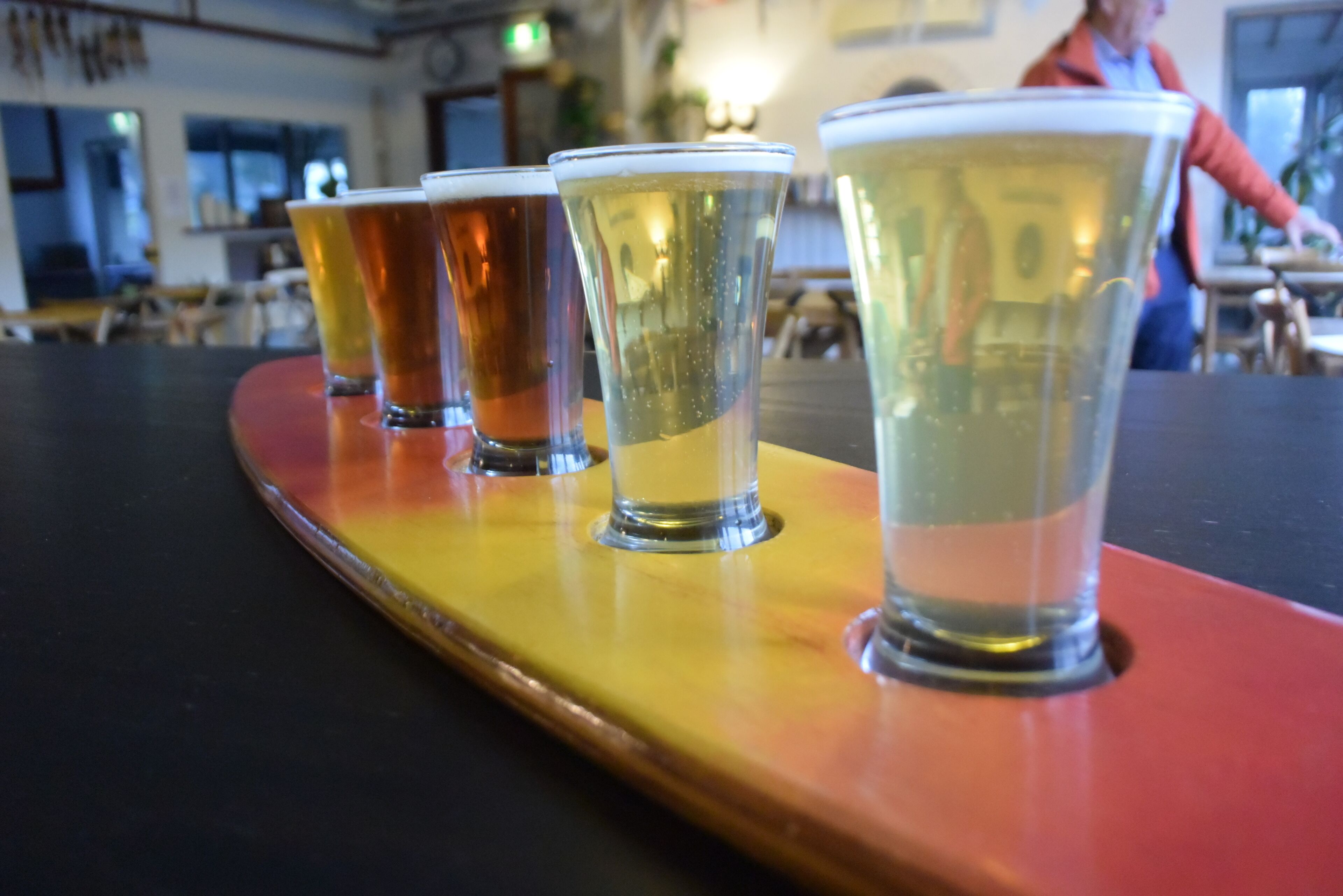 A row of shot glasses on a wooden tray.