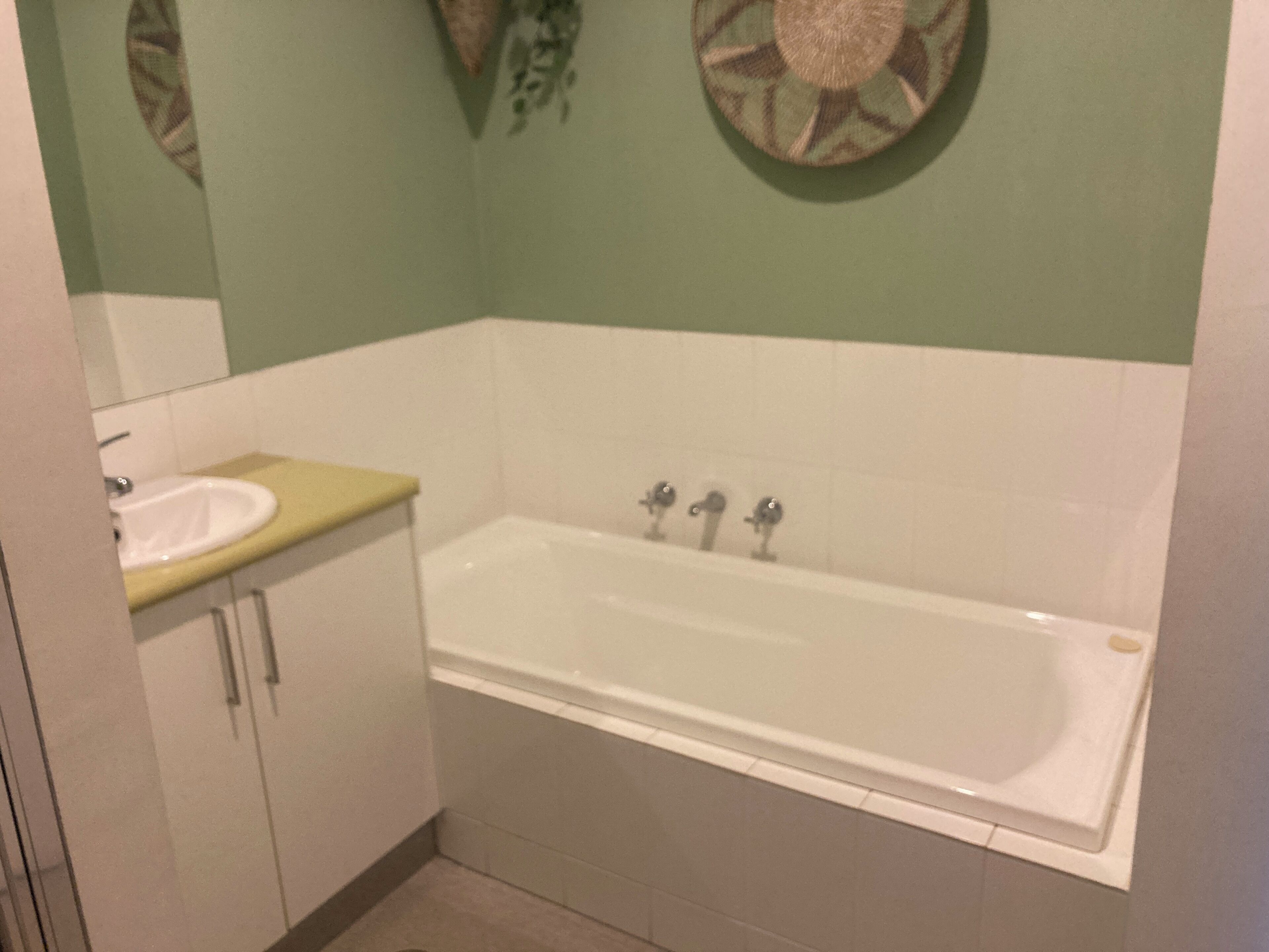 A bathroom with a bathtub, a sink, and a mirror.