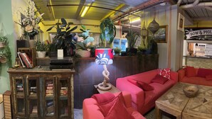 Un intérieur de pub chaleureux avec des canapés rouges, un bar et diverses plantes.
