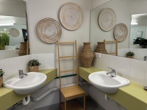 A bathroom with two sinks, a wooden ladder, and woven wall decorations. - Sow and Piglets Guesthouse - Hostel (Port Campbell)