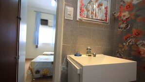 Uma casa de banho com uma pia branca, um espelho e azulejos estampados com flores.