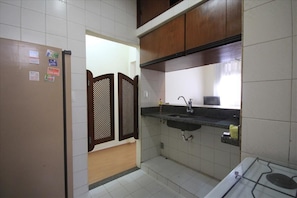 A compact kitchen with a refrigerator, sink, and stove.