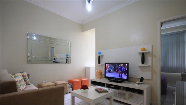 A living room with a sofa, a coffee table, a TV, and a mirror. - Dutra 1104 (Rio de Janeiro)